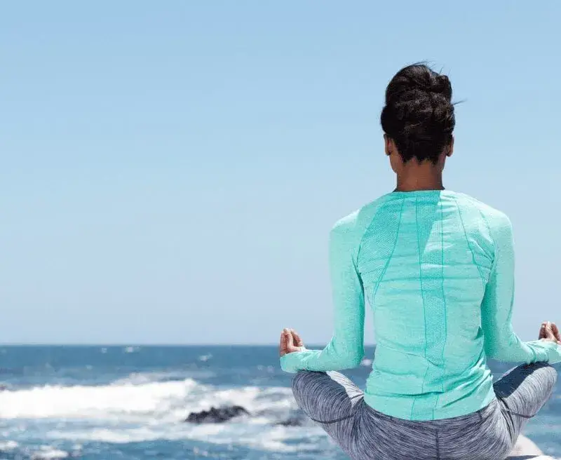woman meditating on the beach